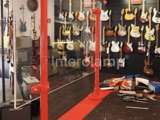 Covid-19 screen protector at a music shop with red powder coated steel tube. Guitars on the wall 