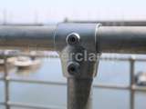 up close picture of a key clamp link onto a hand railing system over looking a marina with boats in 